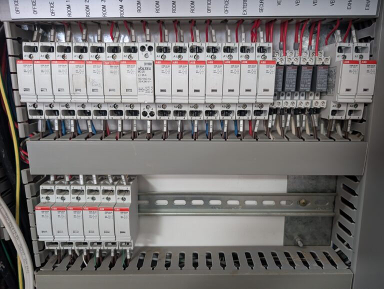 Close-up of commercial switchboard with ABB modular circuit breakers labelled by room