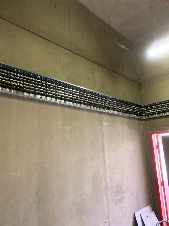 Horizontal cable tray installation along concrete wall with precision-mounted brackets