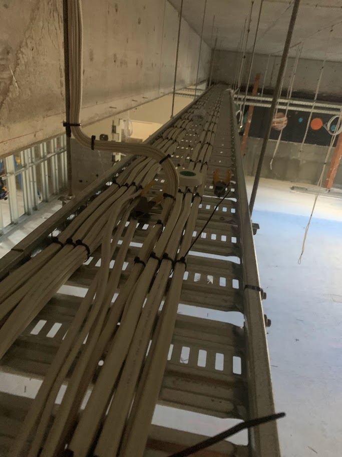 Overhead electrical cable tray with neatly bundled wiring in a commercial building