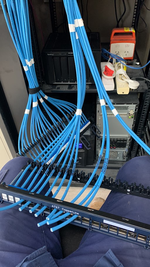 Blue Cat6 data cables being prepared and dressed for termination into an AT&T CopperLine patch panel