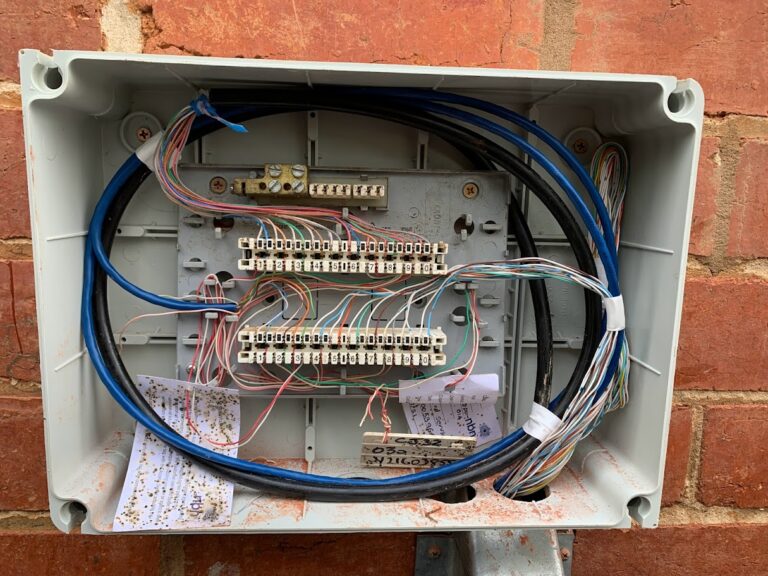 Exposed telephone junction box with labelled punchdown blocks and multicolour cabling