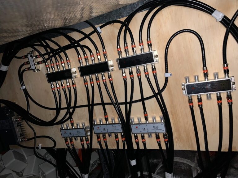 Coaxial cable splitters and signal amplifiers for TV distribution mounted to ply board